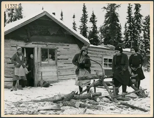 Woman cutting wood outside a log cabin